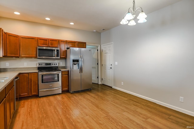 kitchen featuring appliances with stainless steel finishes, a chandelier, light hardwood / wood-style flooring, and hanging light fixtures