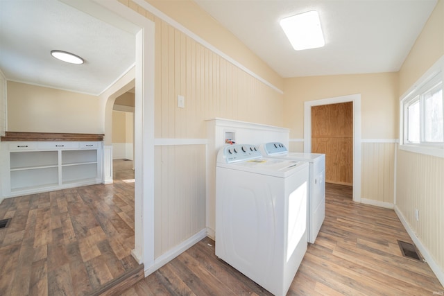 clothes washing area with hardwood / wood-style floors and washing machine and clothes dryer