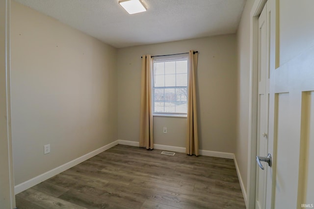 unfurnished room with a textured ceiling and dark hardwood / wood-style flooring