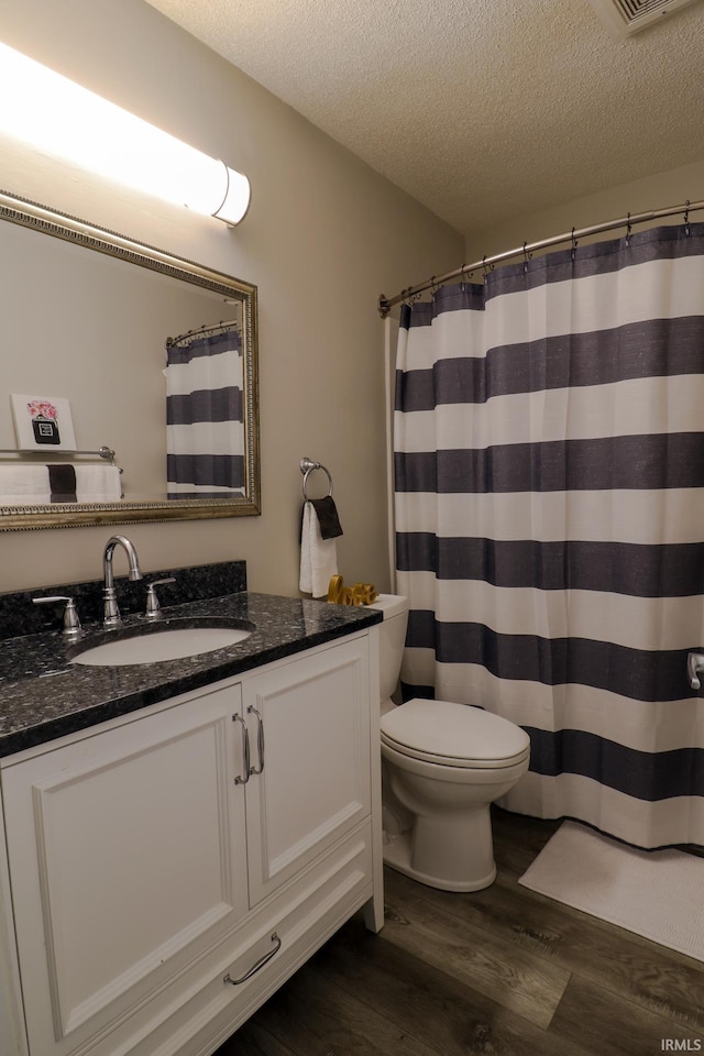 bathroom with toilet, vanity, hardwood / wood-style flooring, a textured ceiling, and a shower with shower curtain