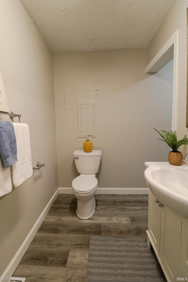 bathroom featuring toilet, vanity, wood-type flooring, and a textured ceiling