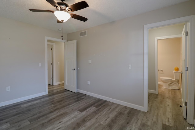 unfurnished bedroom featuring ceiling fan, connected bathroom, a textured ceiling, and hardwood / wood-style floors