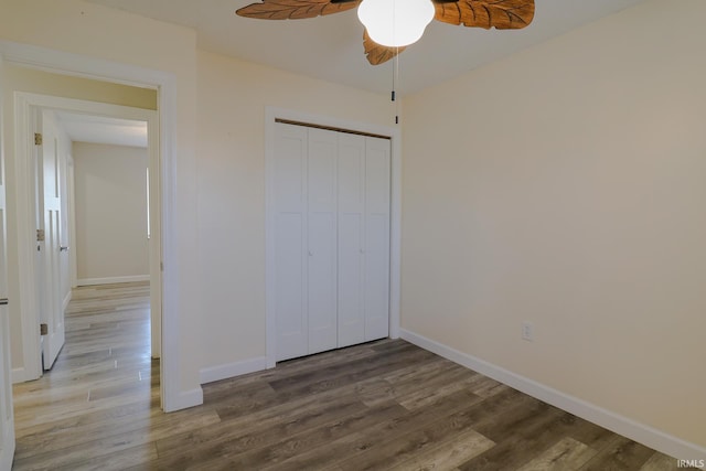 unfurnished bedroom with ceiling fan, a closet, and wood-type flooring