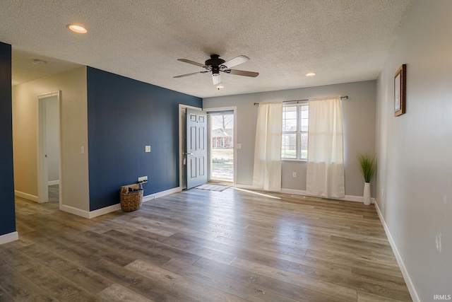 empty room with a textured ceiling, ceiling fan, and hardwood / wood-style flooring