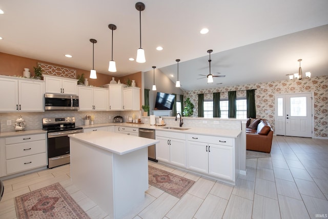 kitchen with kitchen peninsula, appliances with stainless steel finishes, sink, and a center island