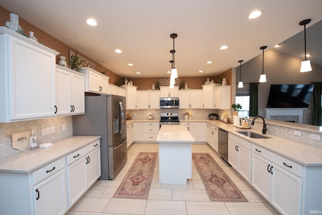 kitchen with hanging light fixtures, white cabinets, sink, and stainless steel appliances