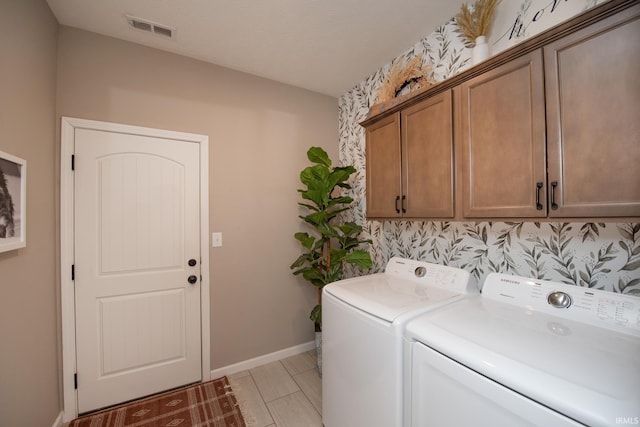 clothes washing area featuring cabinets and independent washer and dryer