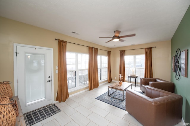 living room featuring ceiling fan and a textured ceiling