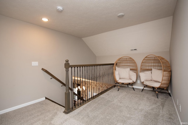 sitting room featuring a textured ceiling, carpet flooring, and lofted ceiling