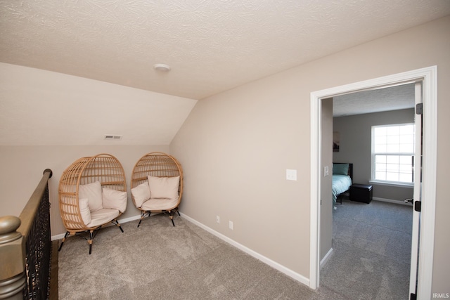 living area with light colored carpet, vaulted ceiling, and a textured ceiling