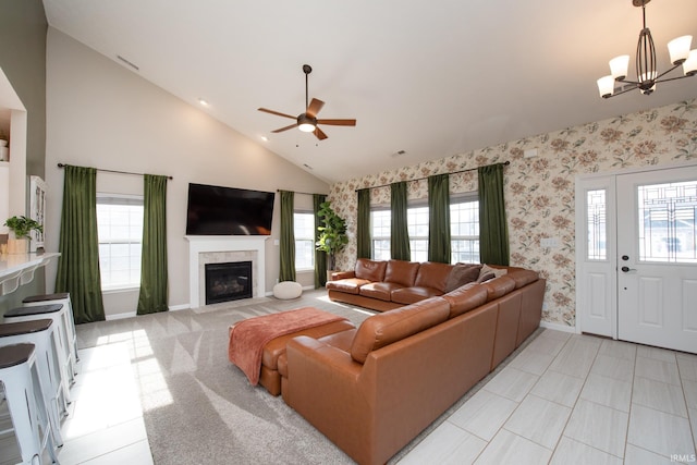 living room with ceiling fan with notable chandelier, plenty of natural light, and high vaulted ceiling