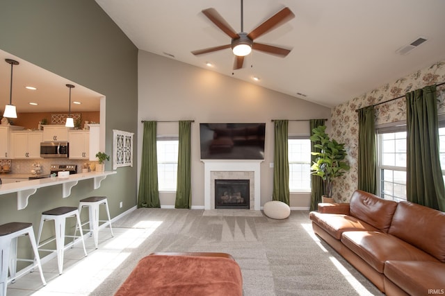 living room featuring vaulted ceiling, a fireplace, light colored carpet, and ceiling fan