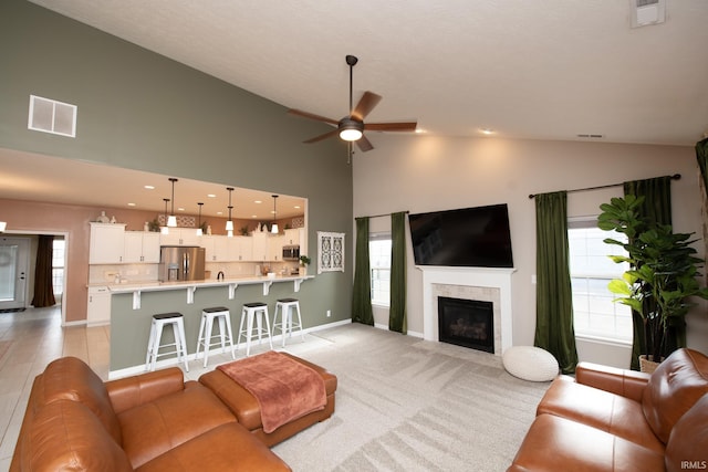 living room with light carpet, ceiling fan, and high vaulted ceiling