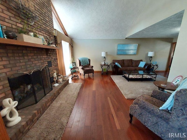 living room featuring a textured ceiling, dark wood-type flooring, vaulted ceiling, and a brick fireplace