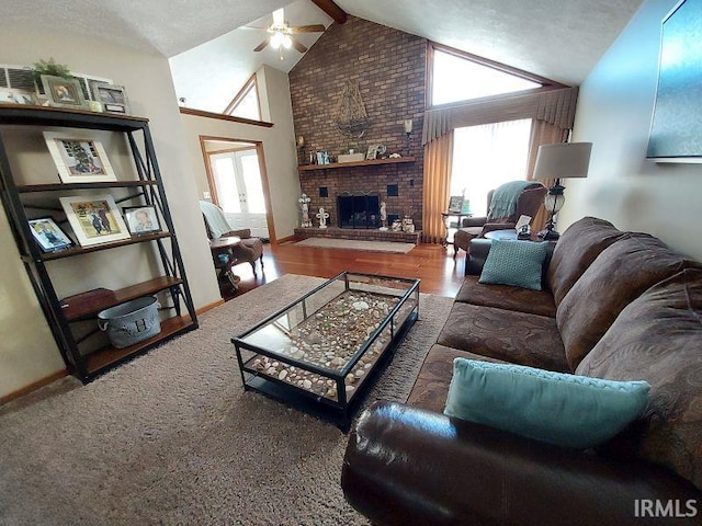 living room featuring a textured ceiling, wood-type flooring, a fireplace, lofted ceiling with beams, and ceiling fan