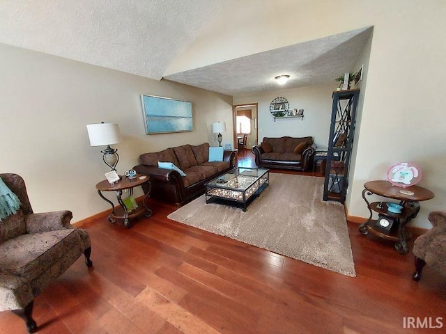 living room with a textured ceiling, hardwood / wood-style floors, and vaulted ceiling