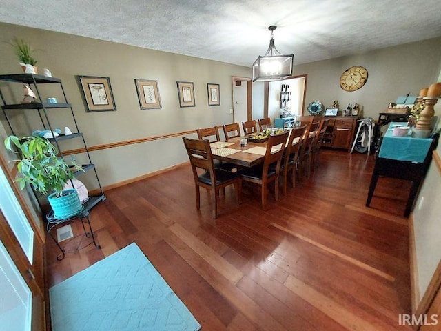 dining room featuring dark wood-type flooring and a textured ceiling