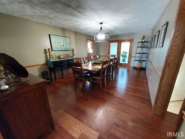 dining room with a textured ceiling and dark hardwood / wood-style floors