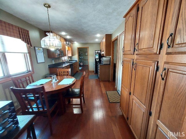 dining area with sink, a textured ceiling, and dark hardwood / wood-style floors