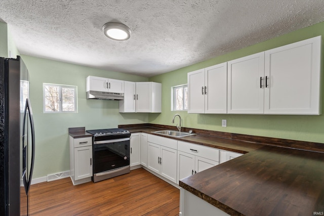 kitchen with wood counters, white cabinetry, appliances with stainless steel finishes, dark hardwood / wood-style flooring, and sink