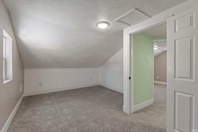 bonus room featuring vaulted ceiling, a textured ceiling, and light colored carpet