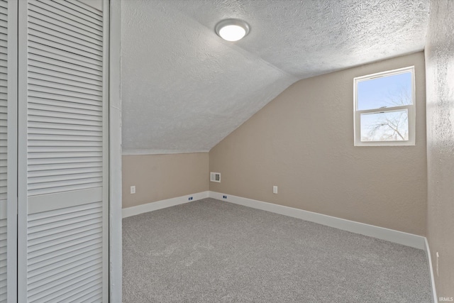 additional living space featuring carpet floors, vaulted ceiling, and a textured ceiling