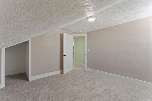 bonus room with light colored carpet, vaulted ceiling, and a textured ceiling