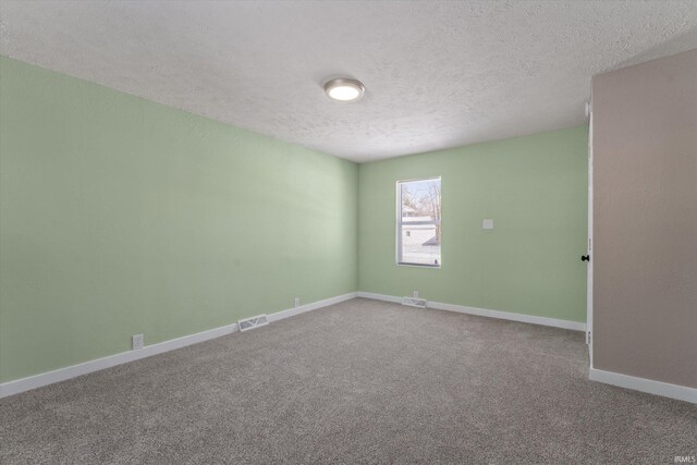 carpeted empty room featuring a textured ceiling