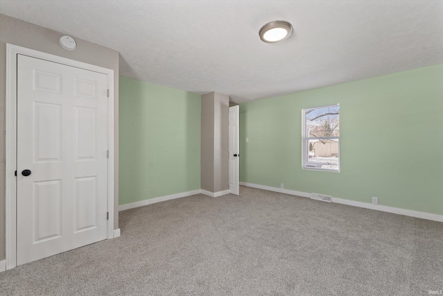 unfurnished bedroom featuring a textured ceiling and light carpet