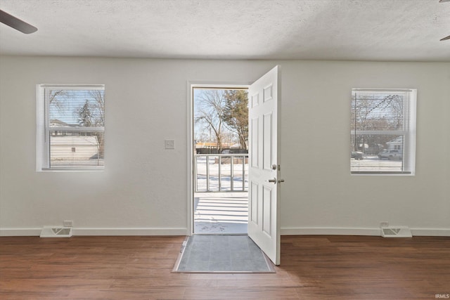 doorway to outside featuring a textured ceiling, ceiling fan, plenty of natural light, and dark hardwood / wood-style floors