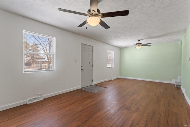 interior space featuring ceiling fan, dark wood-type flooring, and a textured ceiling