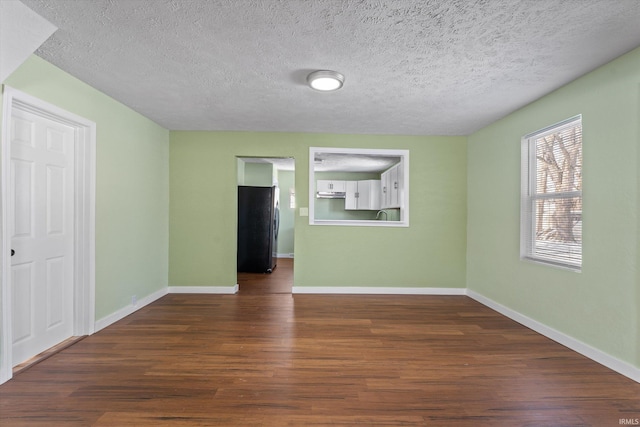 empty room with a textured ceiling and dark hardwood / wood-style flooring