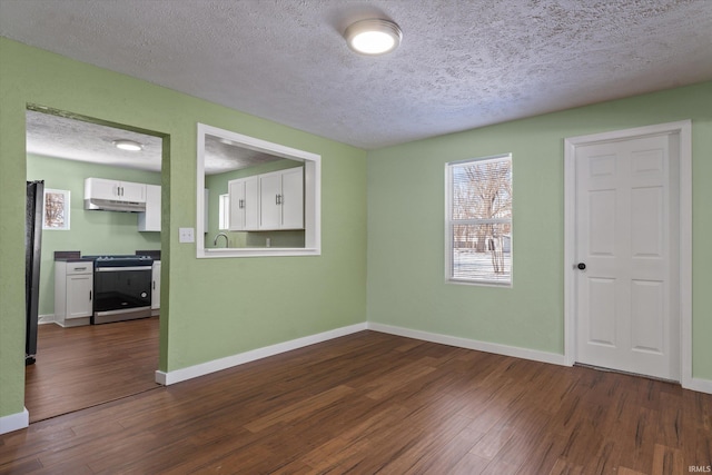 empty room with a textured ceiling and dark hardwood / wood-style flooring