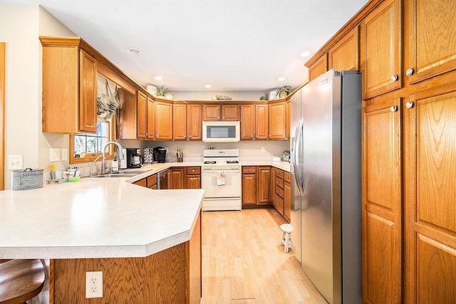 kitchen with stainless steel fridge, white range with gas stovetop, a kitchen breakfast bar, light hardwood / wood-style floors, and kitchen peninsula