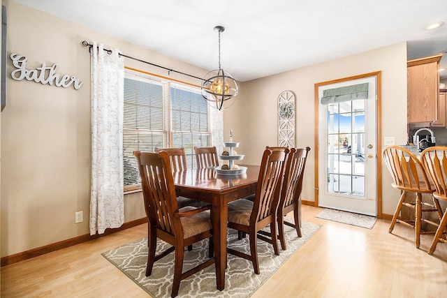 dining room featuring a healthy amount of sunlight, a chandelier, and light wood-type flooring