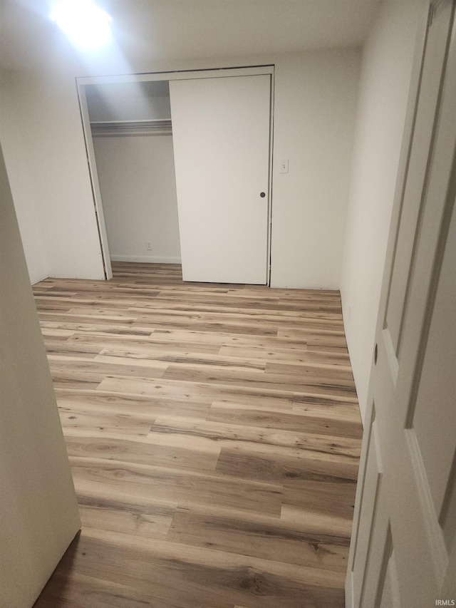 unfurnished bedroom with a closet and light wood-type flooring