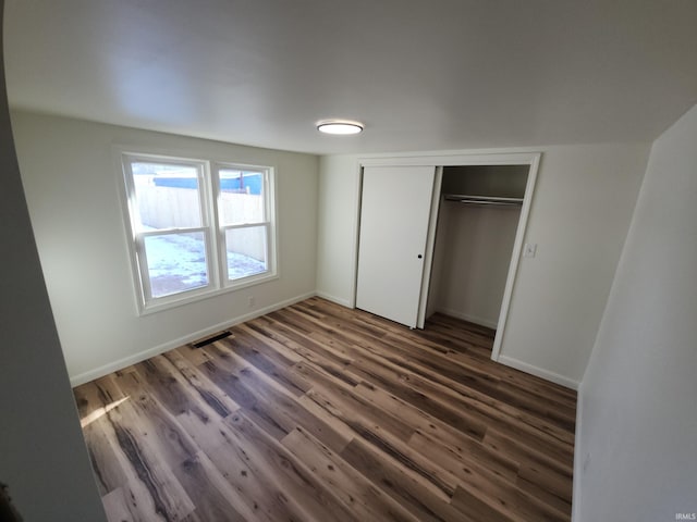 unfurnished bedroom featuring dark hardwood / wood-style flooring and a closet