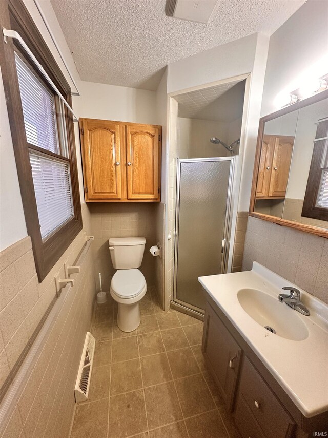 bathroom with vanity, a textured ceiling, tile walls, and walk in shower