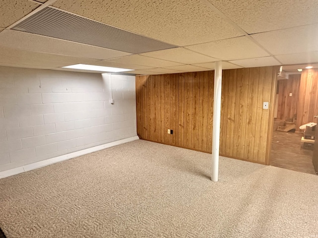 basement with a paneled ceiling, carpet, and wooden walls