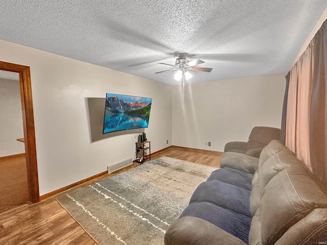 living room featuring ceiling fan, a textured ceiling, and hardwood / wood-style floors