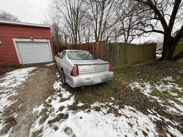 snow covered parking area with a garage