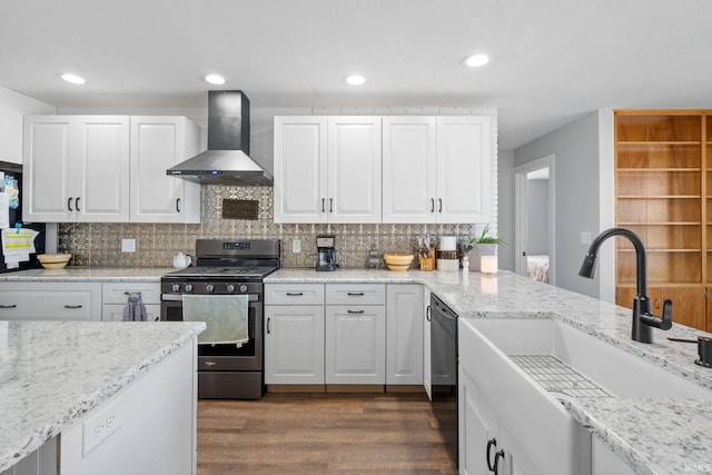 kitchen featuring gas range, sink, wall chimney range hood, and white cabinetry