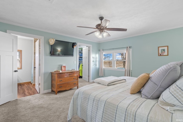 bedroom featuring ceiling fan, ensuite bathroom, ornamental molding, light carpet, and a walk in closet