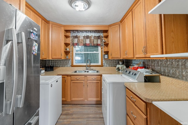 clothes washing area featuring sink, separate washer and dryer, and light hardwood / wood-style flooring