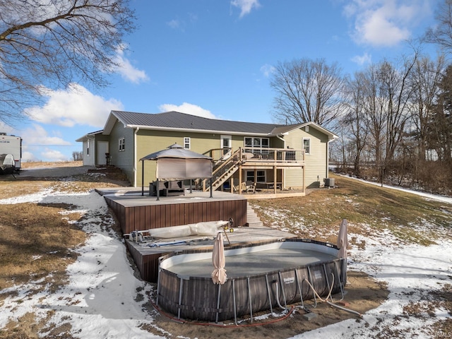 snow covered property with a deck, central AC, and a hot tub