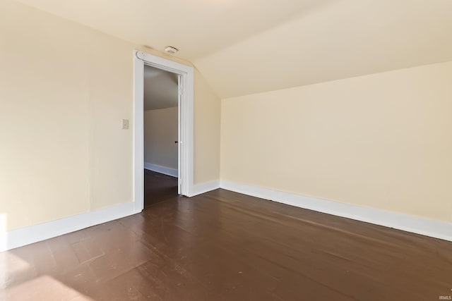 unfurnished room featuring dark wood-type flooring and lofted ceiling