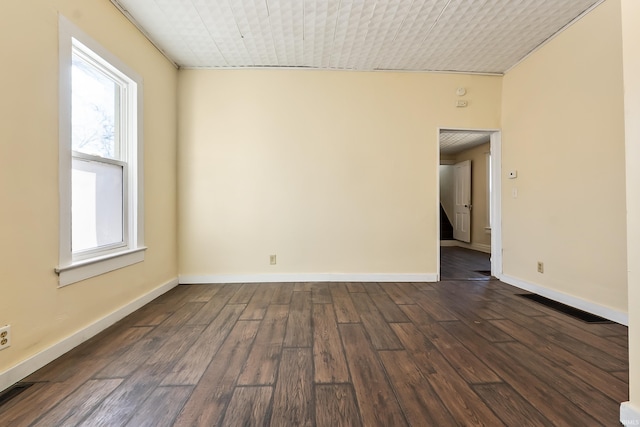 spare room featuring dark wood-type flooring and plenty of natural light