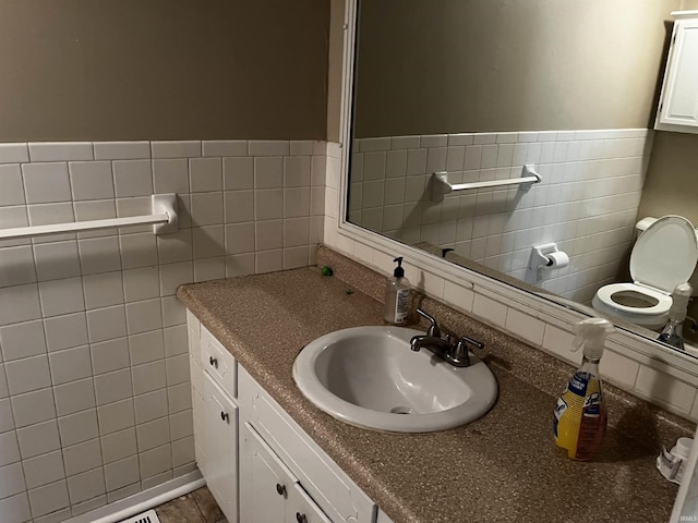 bathroom with tile walls, toilet, and vanity