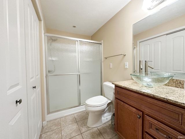 bathroom featuring toilet, tile patterned flooring, an enclosed shower, and vanity