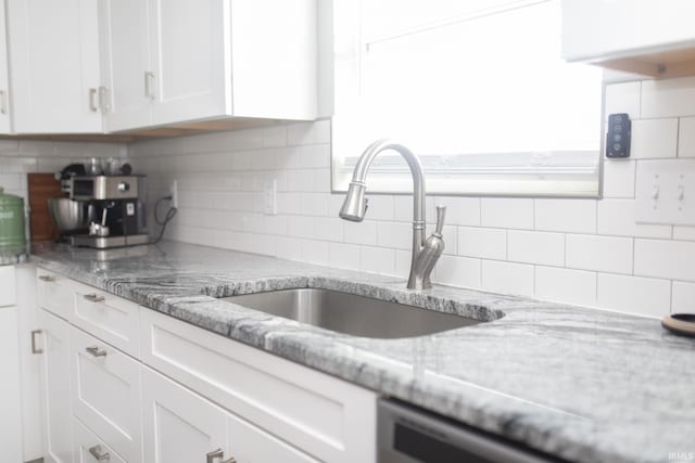 kitchen featuring white cabinets, light stone counters, tasteful backsplash, and sink